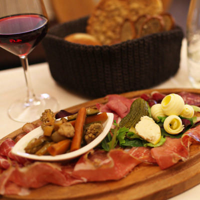 A glass of red wine and an antipasti plate