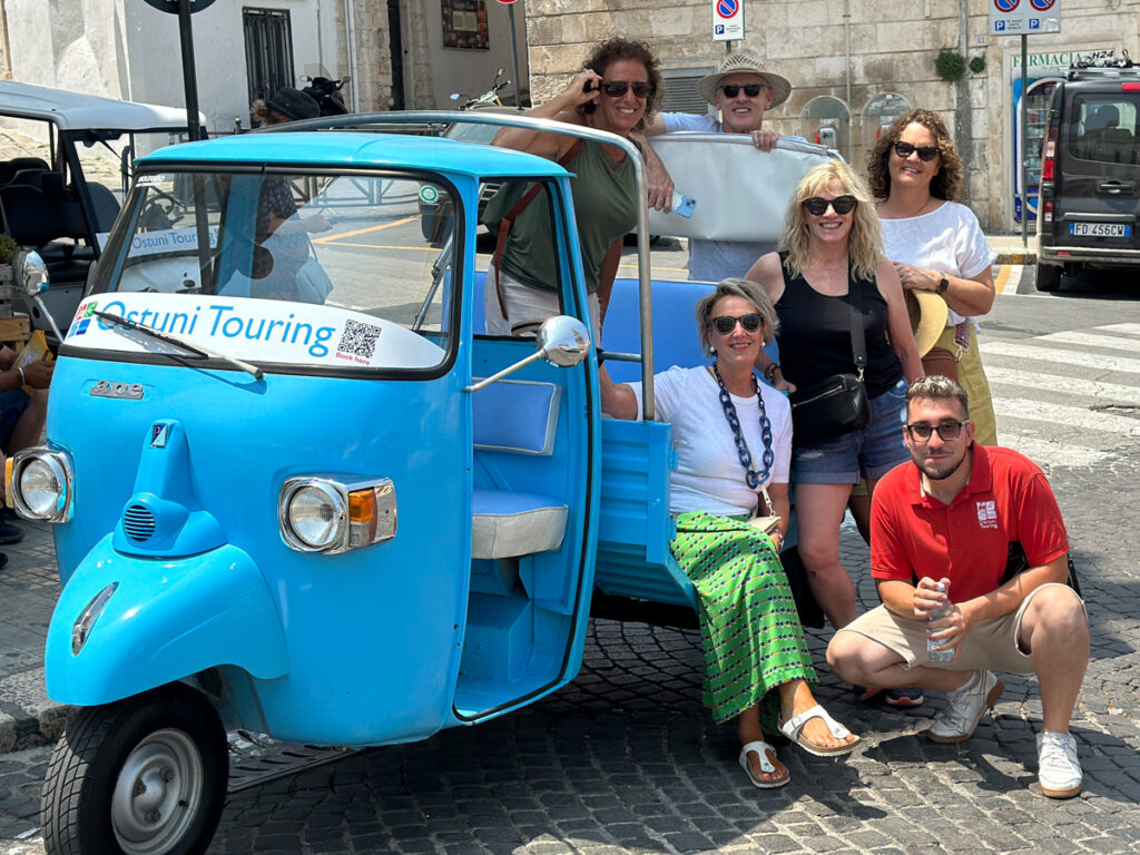 a group of people sitting on a small motorbike after a city tour of Ostuni, Puglia