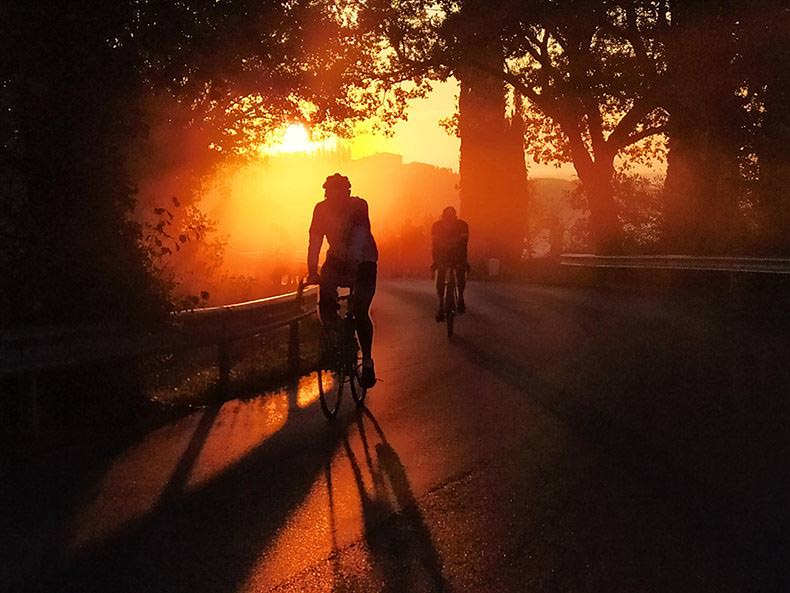A silhouette of a cyclist riding at sunrise