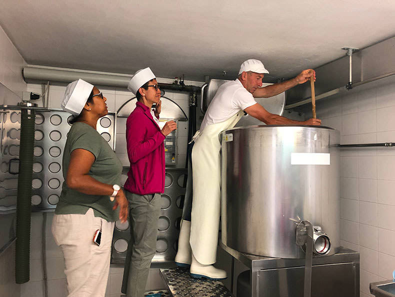 two women watch how cheese is made in the Dolomites