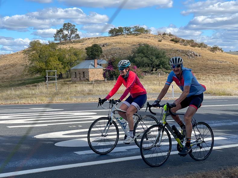 two people riding past a stone house