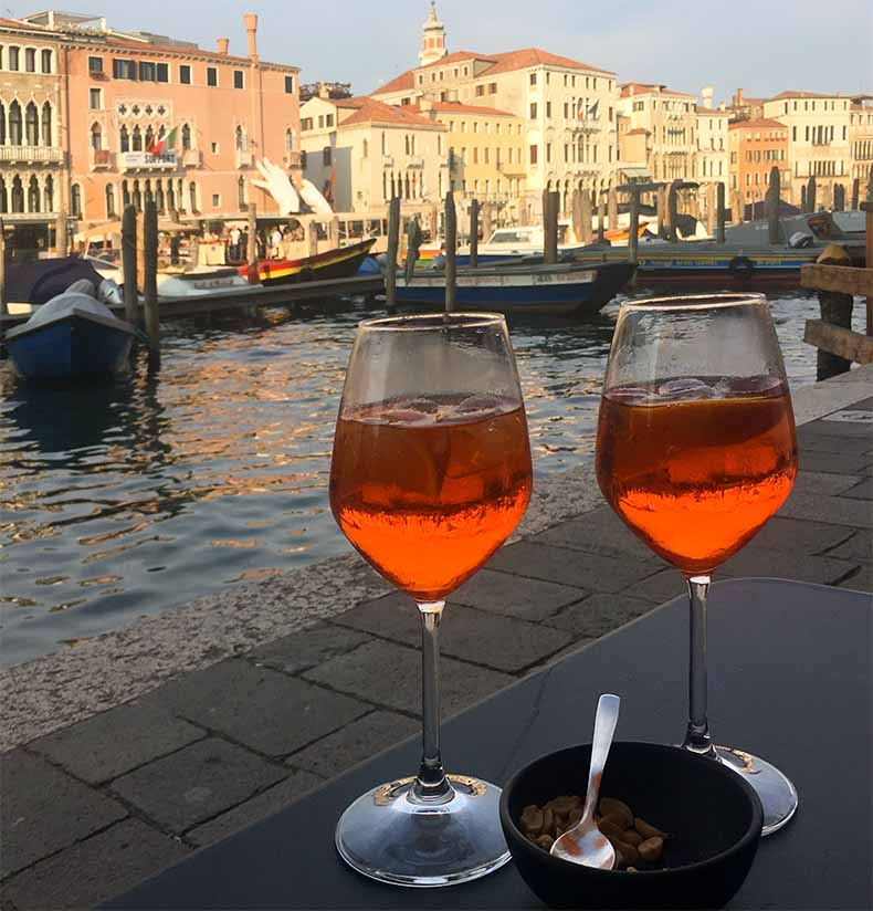 Two glasses of Aperol spritz with a view of the main canal in veince