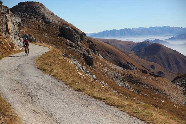 A cyclist riding down the road of Colle Fauniera