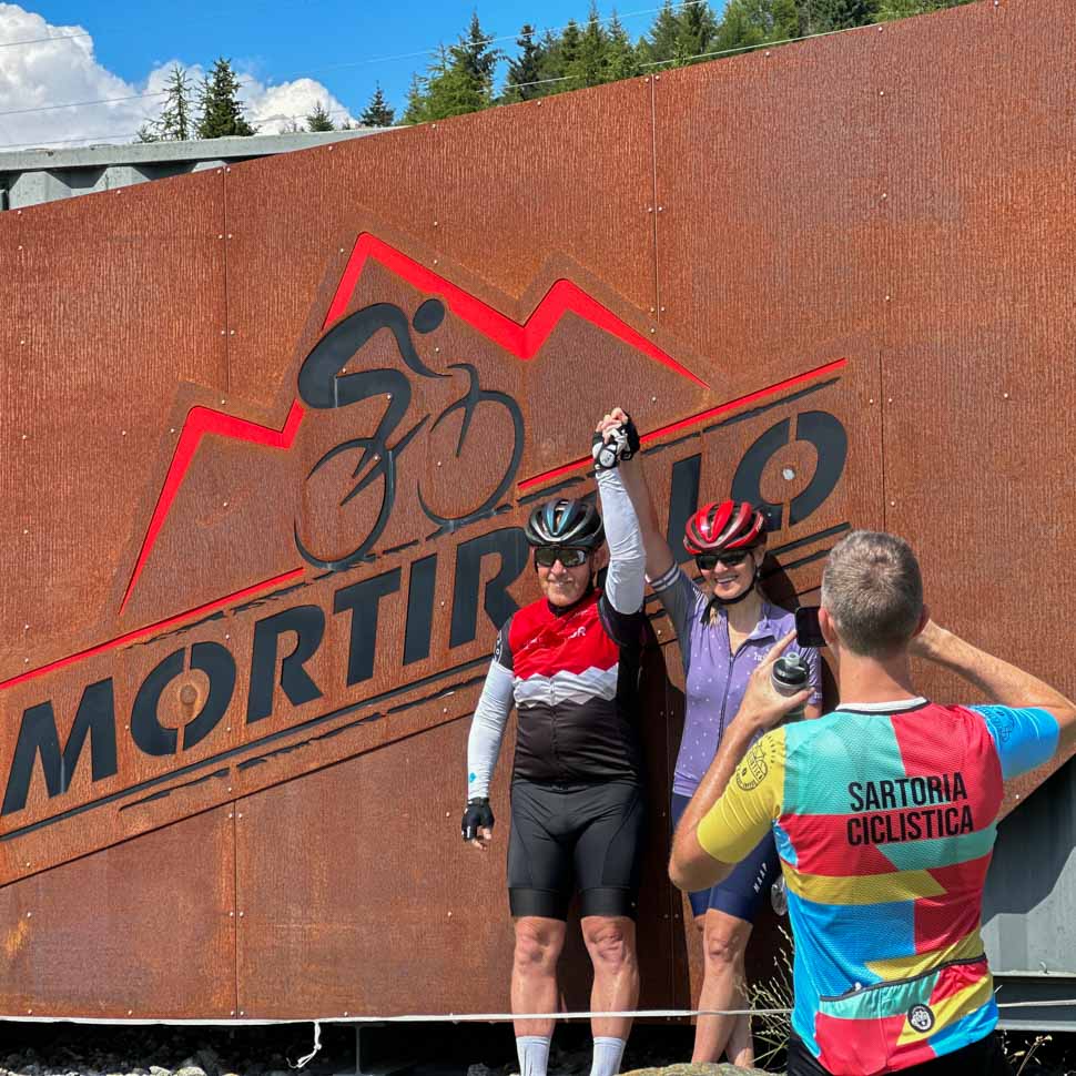 Two people standing in front of the Mortirolo sign in Italy