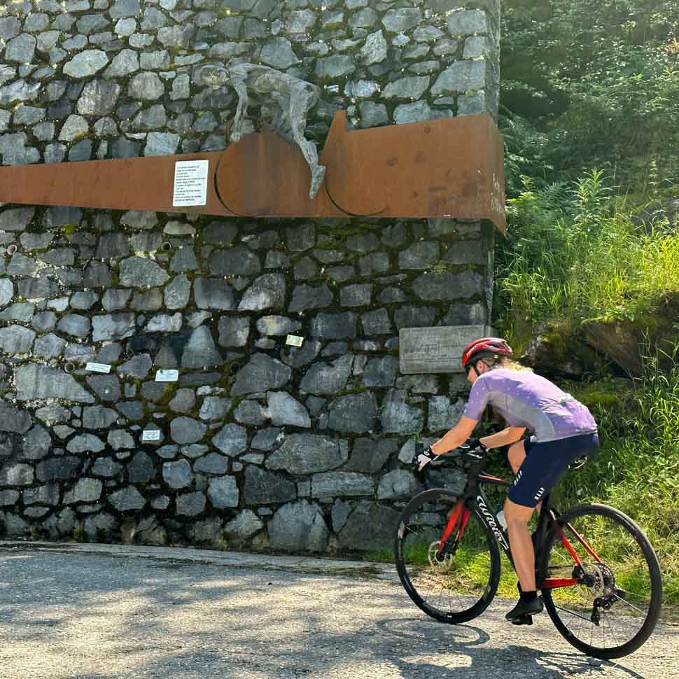 A cyclist riding past the Pantani monument on the Mortirolo in Italy