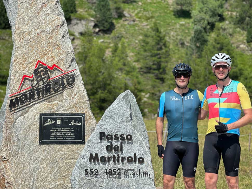 Two riders in front of the monument at the top Passo del Mortirolo