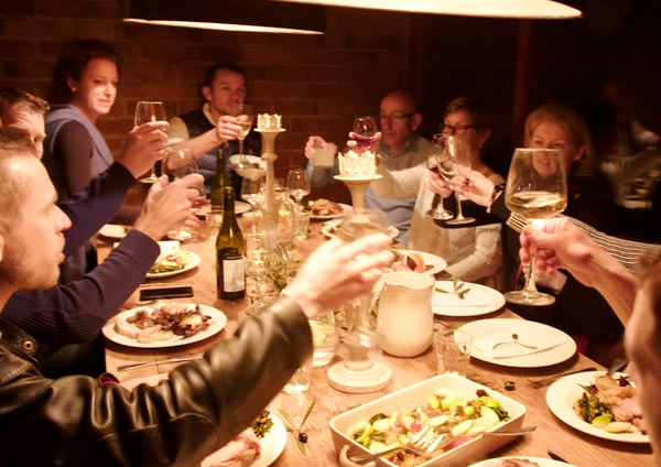 people at dinner clinking glasses