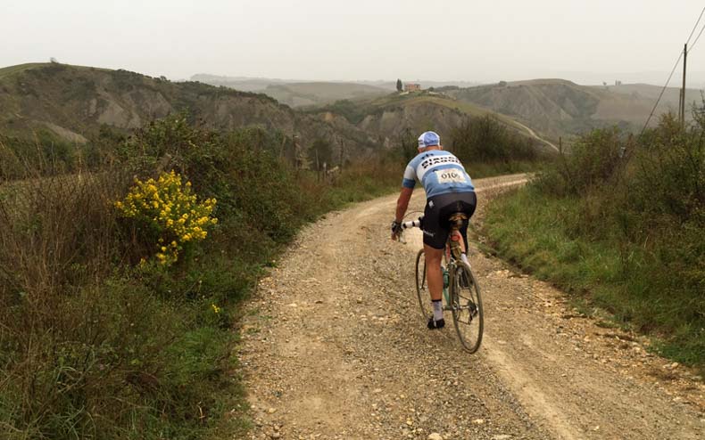 A man cycling on a steel bike on gravel during L'Eroica