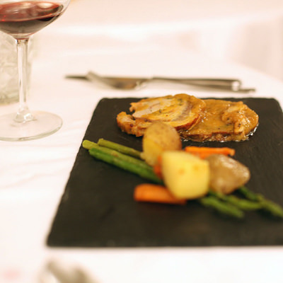 A plate of porchetta and vegetable with a glass of vino rosso