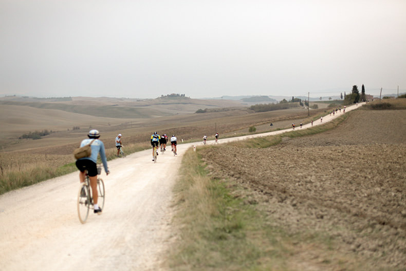 Cyclists riding on the gravel Strade Bianche during L'Eroica
