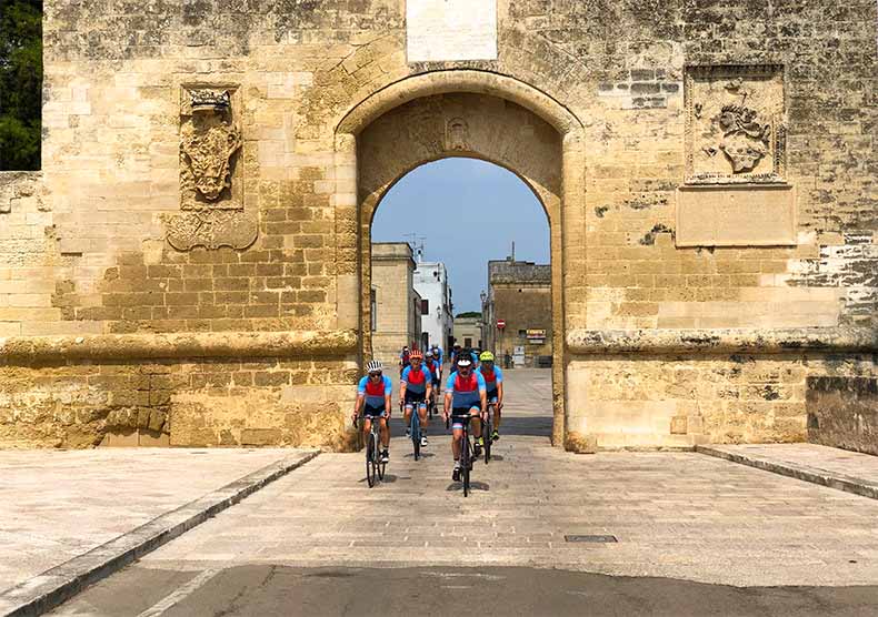 A group of cyclists riding through an old Puglian town on a cycling holiday in Italy