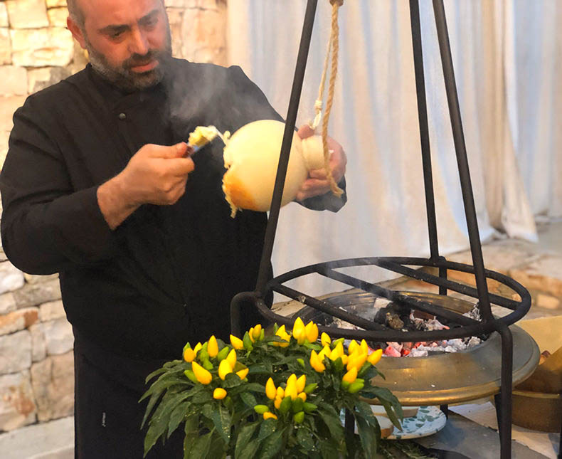 A chef with caciocavallo cheese hanging over a small fire