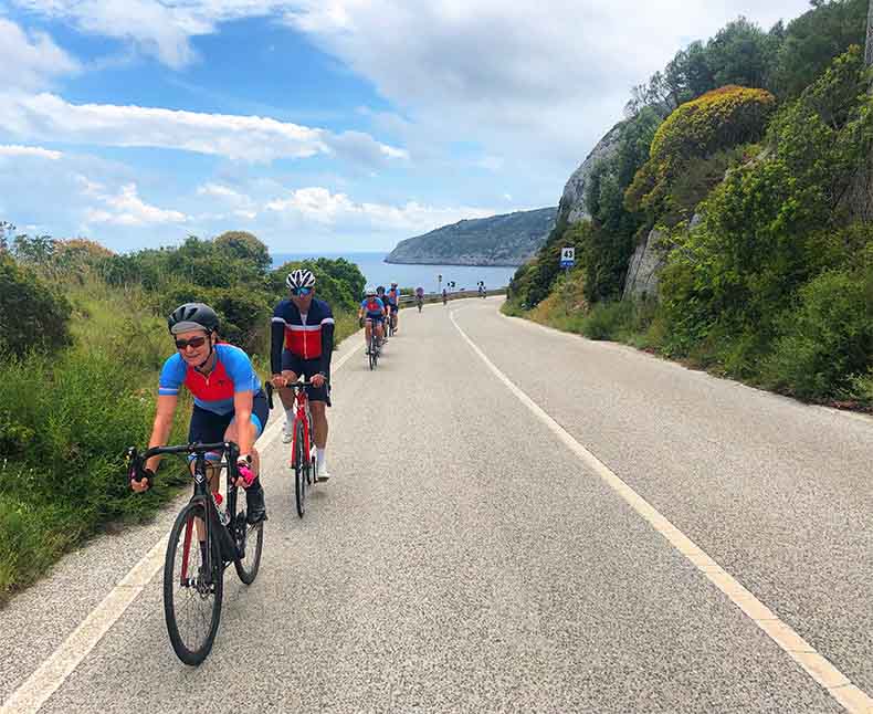 a group of cyclist riding along the coast with the sea to their side