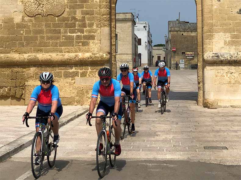 A group of cyclists riding through a town in Puglia Italy