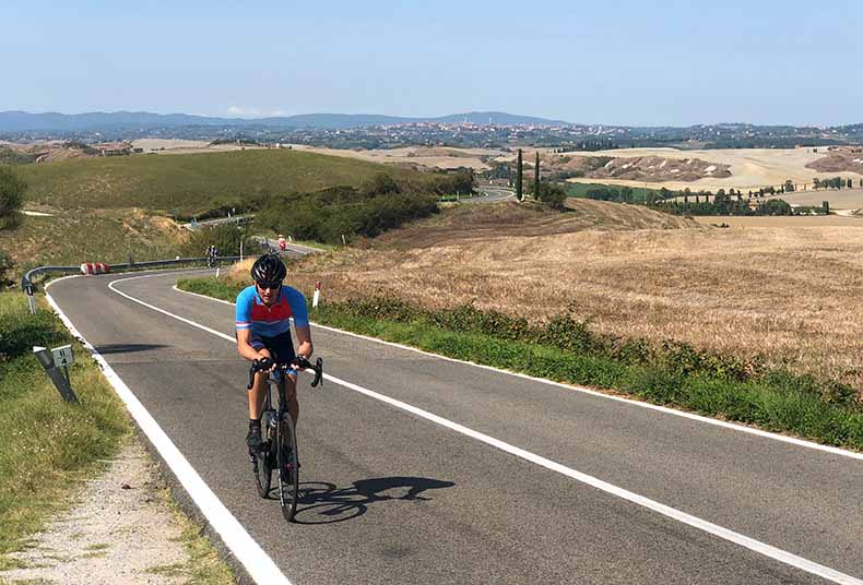a riding cycling up a hill in the Crete Sinese of Tuscany