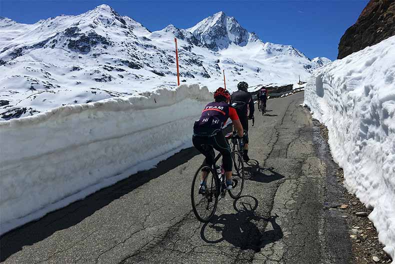 cyclists riding up the snow lined road to Passo Gavia