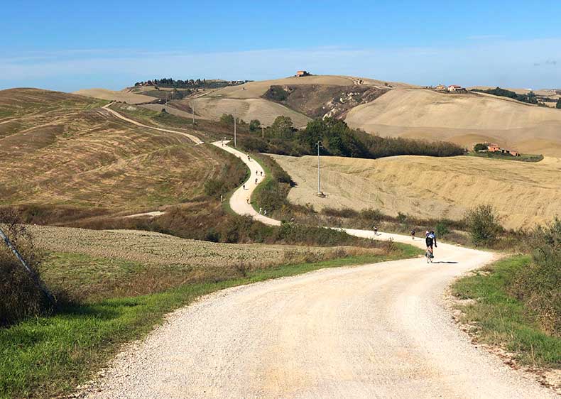 The gravel strade Bianche of tuscany with a cyclist in the distance