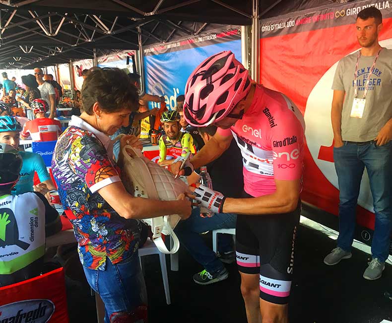 Tom Dumoulin in the giro d'italia pink jersey signing an autograph for a fan