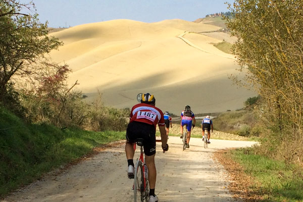 Riders descending the hills of the Val d'orcia in Tuscany during eroica