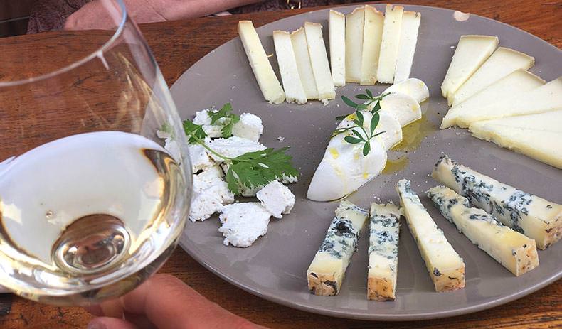 A glass of wine and plate of cheese at a tasting