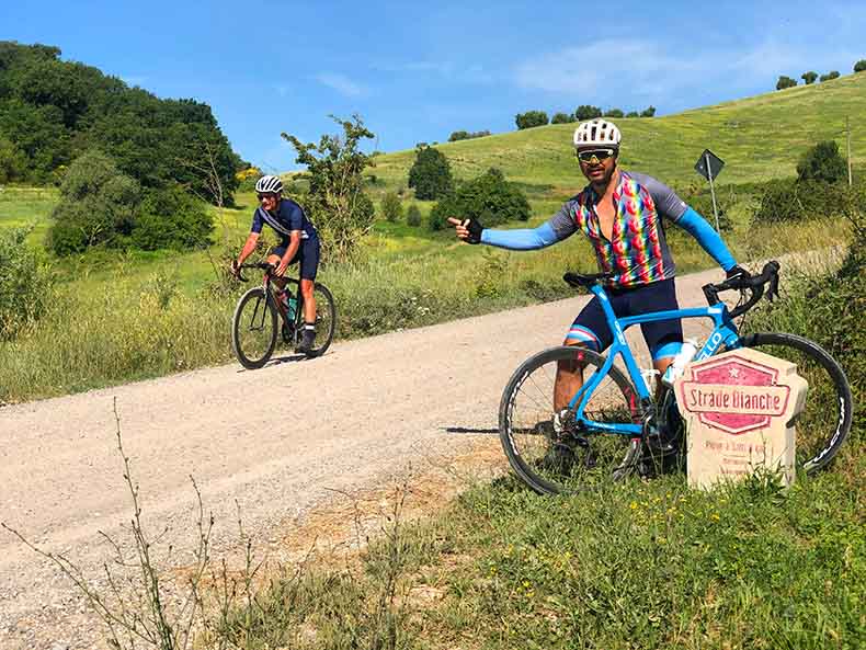 Riders on the gravel beside a L'eroica Strade Bianche marker