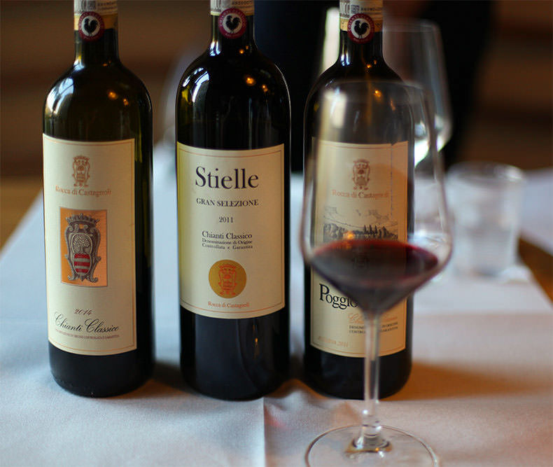 three bottles of wine and a glass at a wine tasting in Tuscany