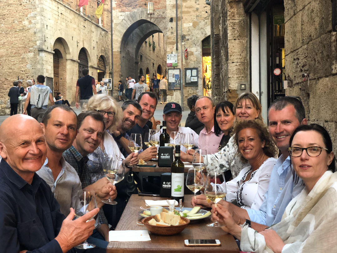 a group of people drinking wine in the cobble stone streets of San Gimignano