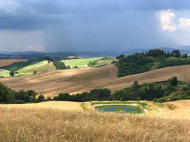 The rolling hills of Tuscany with a rain in the distance