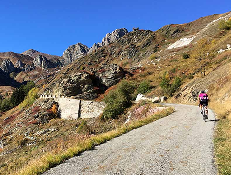 a cyclist riding up Colle Fauniera in Autumn