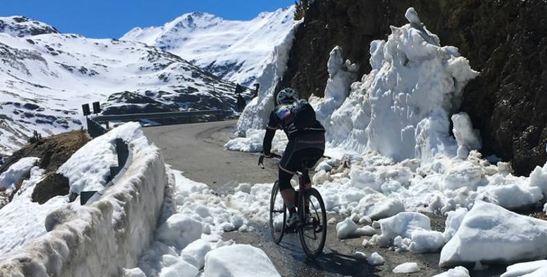 A cyclist riding through snow on the road to Passo Gavia