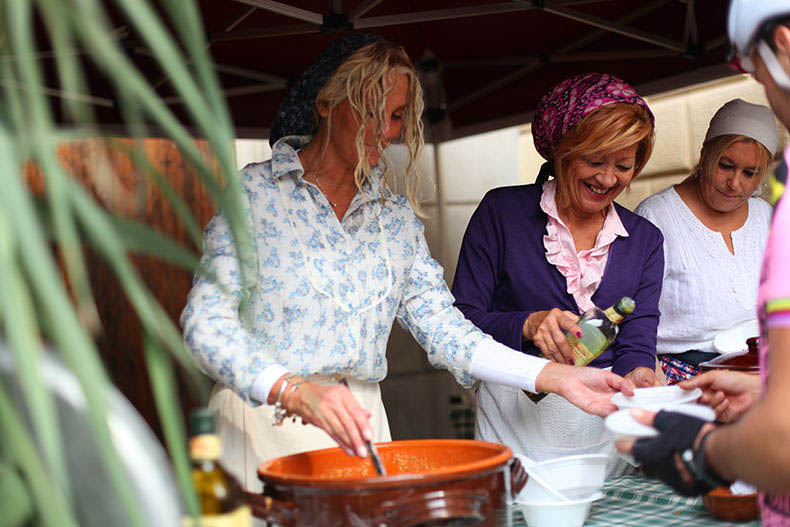 Two ladies serving soup to cyclist at L'Eroica