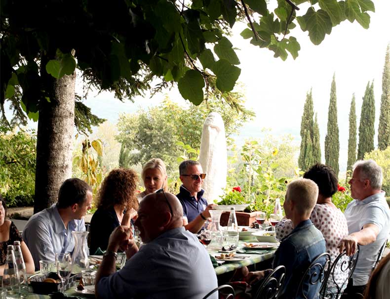 a group of people having a long lunch in Tuscany