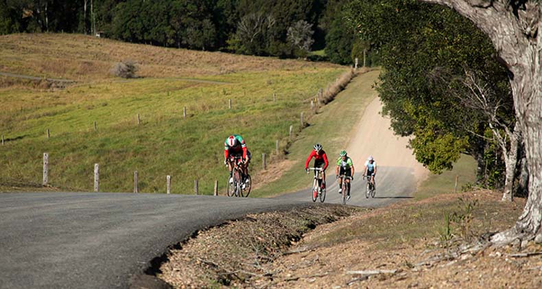 bicycle riders cycling up a very steep hill near noosa