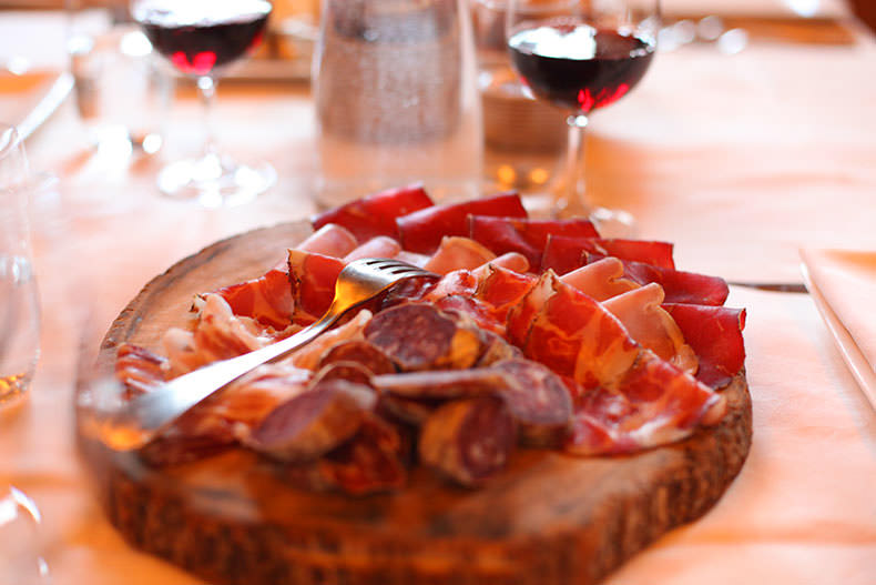 A Italian salumi board with two glasses of wine