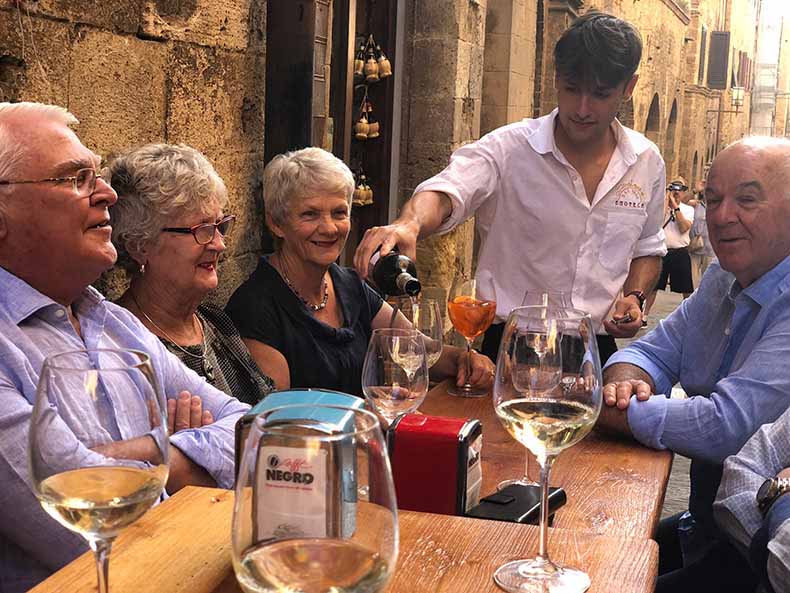 People drinking a glass of wine outside in an Italian Street