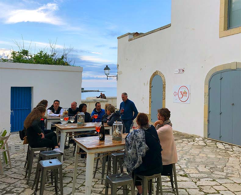 a group of people have aperitivo in Otranto overlooking the water