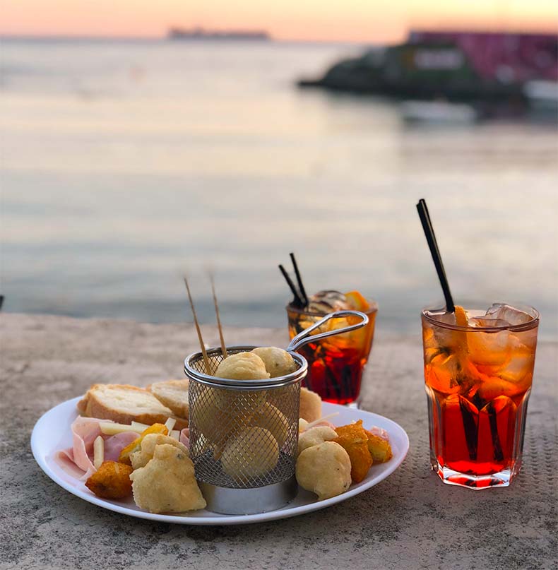 Aperol spritz and aperitivo by the water at sunset near Genoa