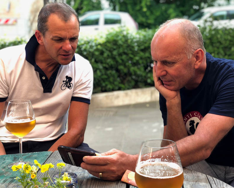 Two people looking at a phone and drinking beer during aperitivo