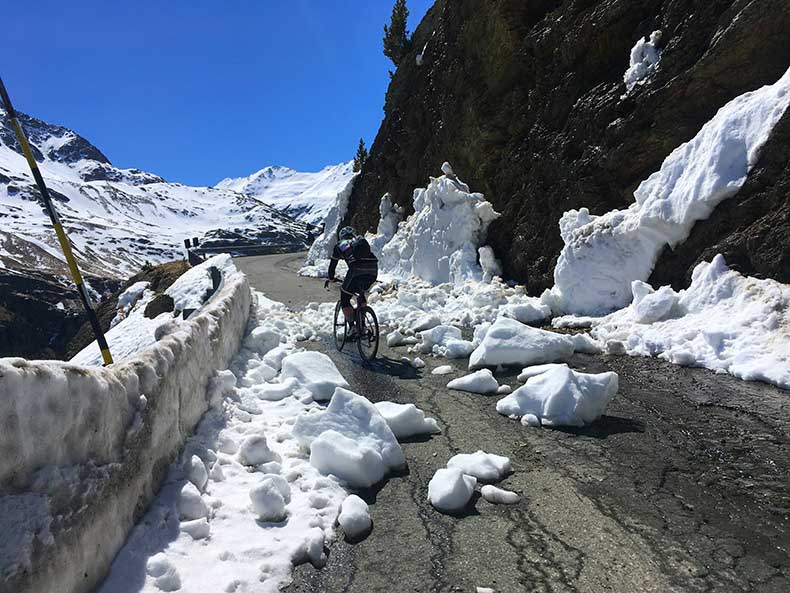 A cyclist riding through snow on the Passo Gavia ascent