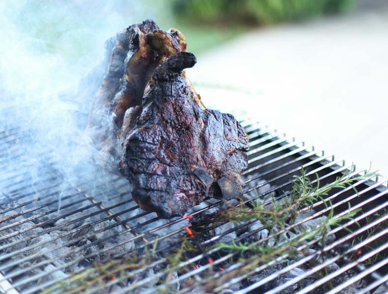 Bistecca alla fiorentina being cooked over charcoal