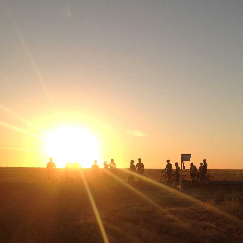 A group of cyclists at sunrise in the Australian outback