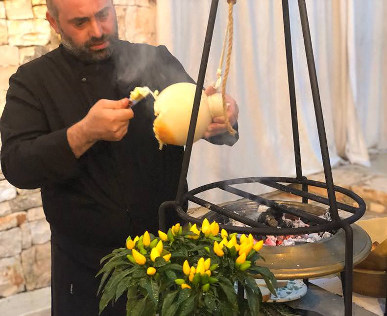 a chef removing soft caciocavallo cheese that has been hanging over charcoal