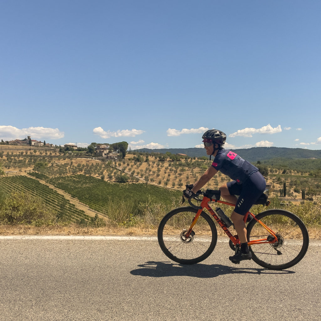 A rider cycling pastthe olive groves of Chianti, Tuscany