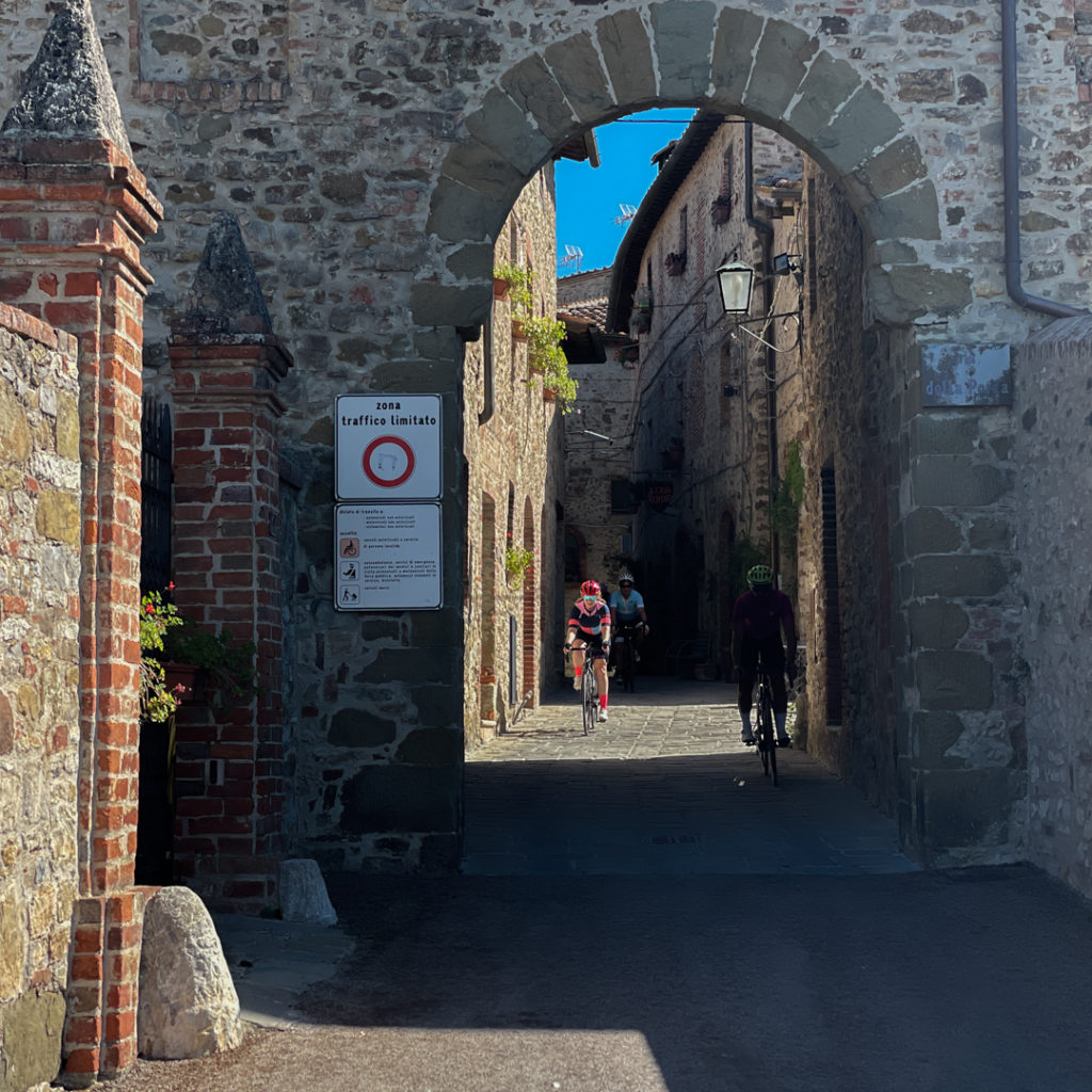 A rider cycling through a stone hamlet in Tuscany