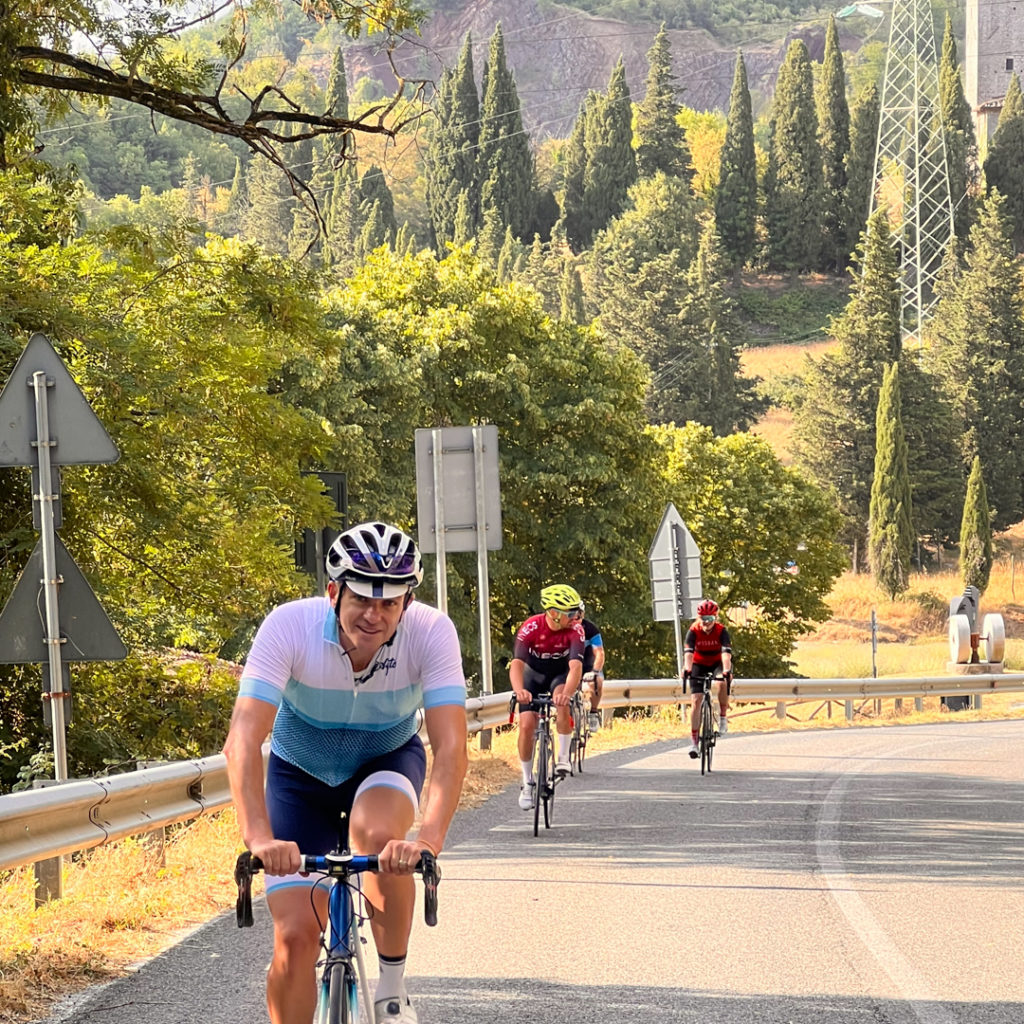 riders cycling up a hill in tuscany