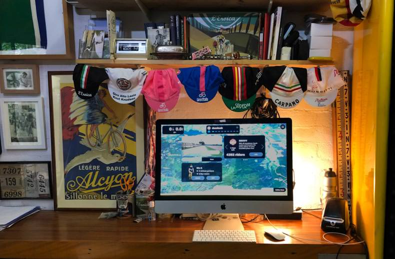 vintage cycling caps in an office with a computer screen displaying an indoor cycling app