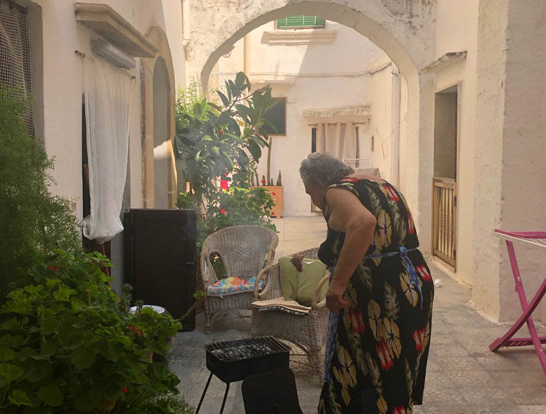 A lady cooking on charcoal in a white washed town of Puglia