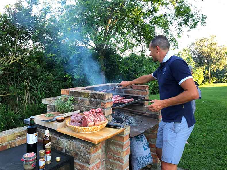 a man cooking a Tuscan BBQ with fire and charcoal