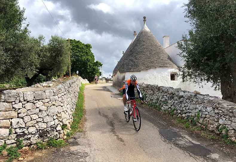 A cyclist riding past a Trulli house in Puglia, Italy