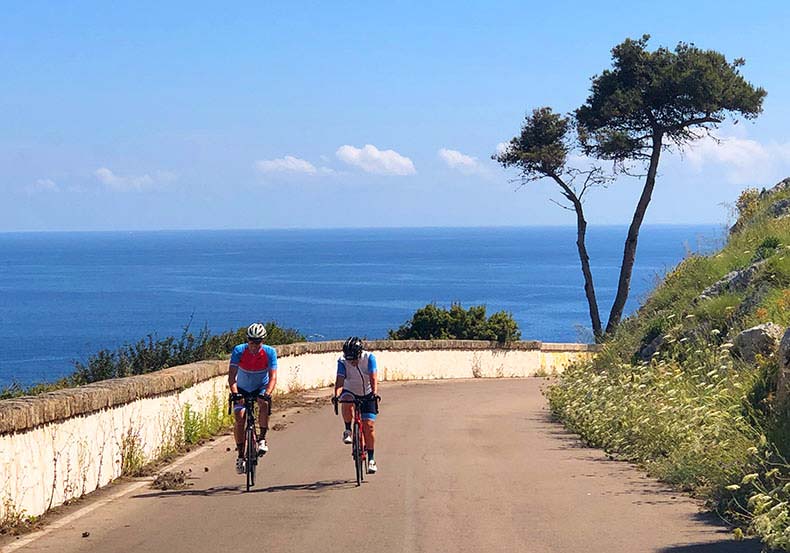 Two riders cycling along the Southern Italian coastline of Puglia